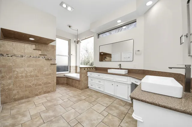 a large bathroom with a granite countertop sink a toilet a mirror and bathtub