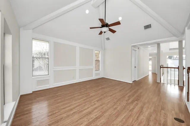 a view of empty room with wooden floor and fan