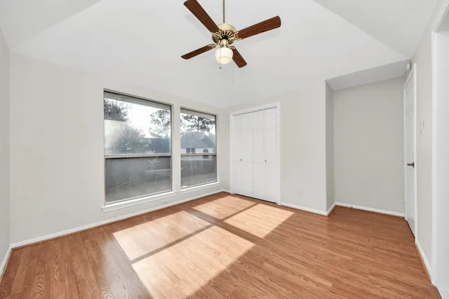 a view of empty room with wooden floor and fan