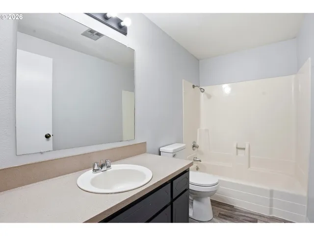 a bathroom with a granite countertop sink toilet a large mirror and shower