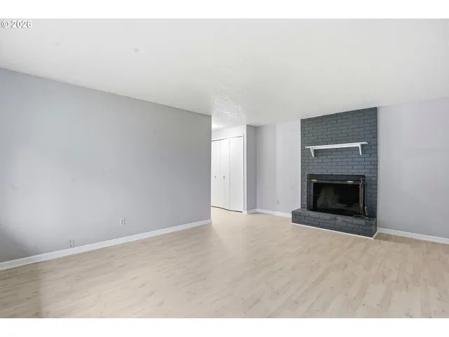a view of an empty room with a fireplace and a window