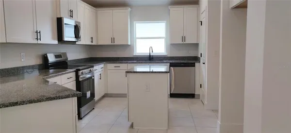 a kitchen with a stove top oven a sink a counter space and cabinets