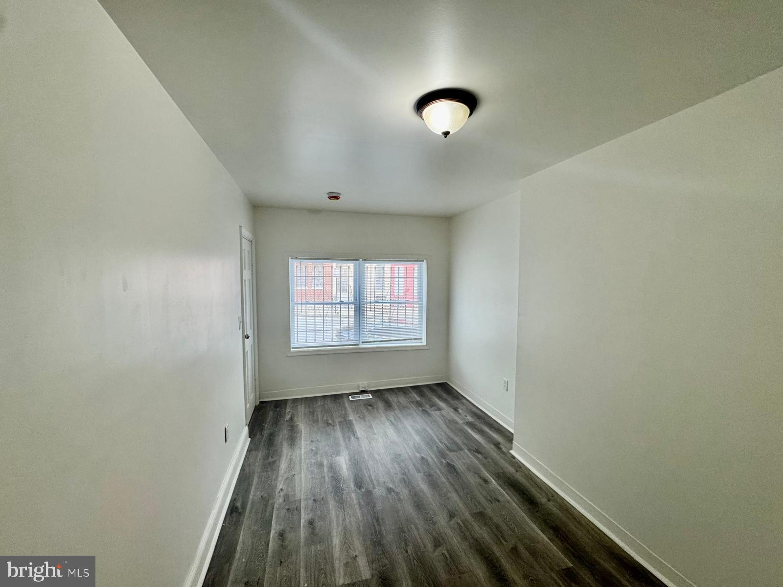 1527 Riggs Avenue Baltimore, MD 21217 - Photo 9 of 16 an empty room with wooden floor and windows