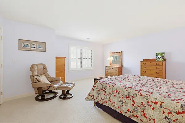a bedroom with a bed a table chair and windows
