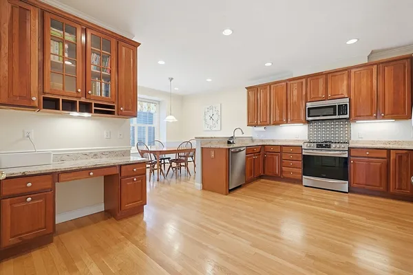 a kitchen with stainless steel appliances granite countertop wooden cabinets a stove a sink and a microwave