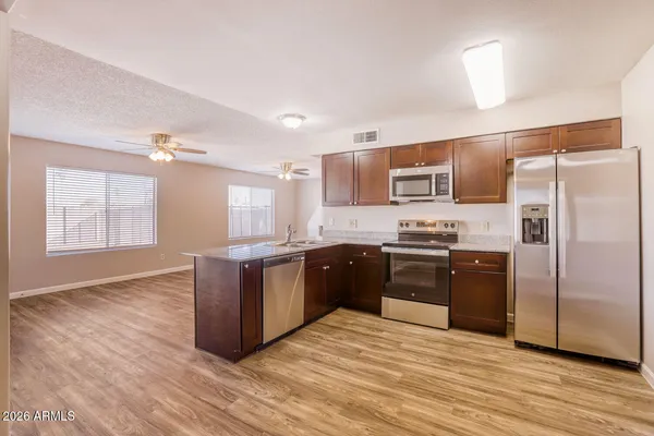 a kitchen with stainless steel appliances granite countertop a refrigerator a sink dishwasher a stove with wooden floors and a fireplace