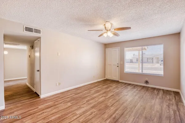 a view of empty room with wooden floor and fan
