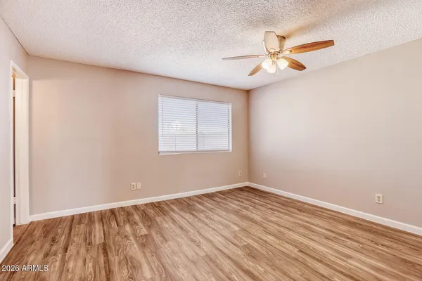 a view of an empty room with wooden floor and a ceiling fan