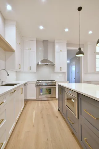 a large kitchen with stainless steel appliances kitchen island a large counter top and a refrigerator