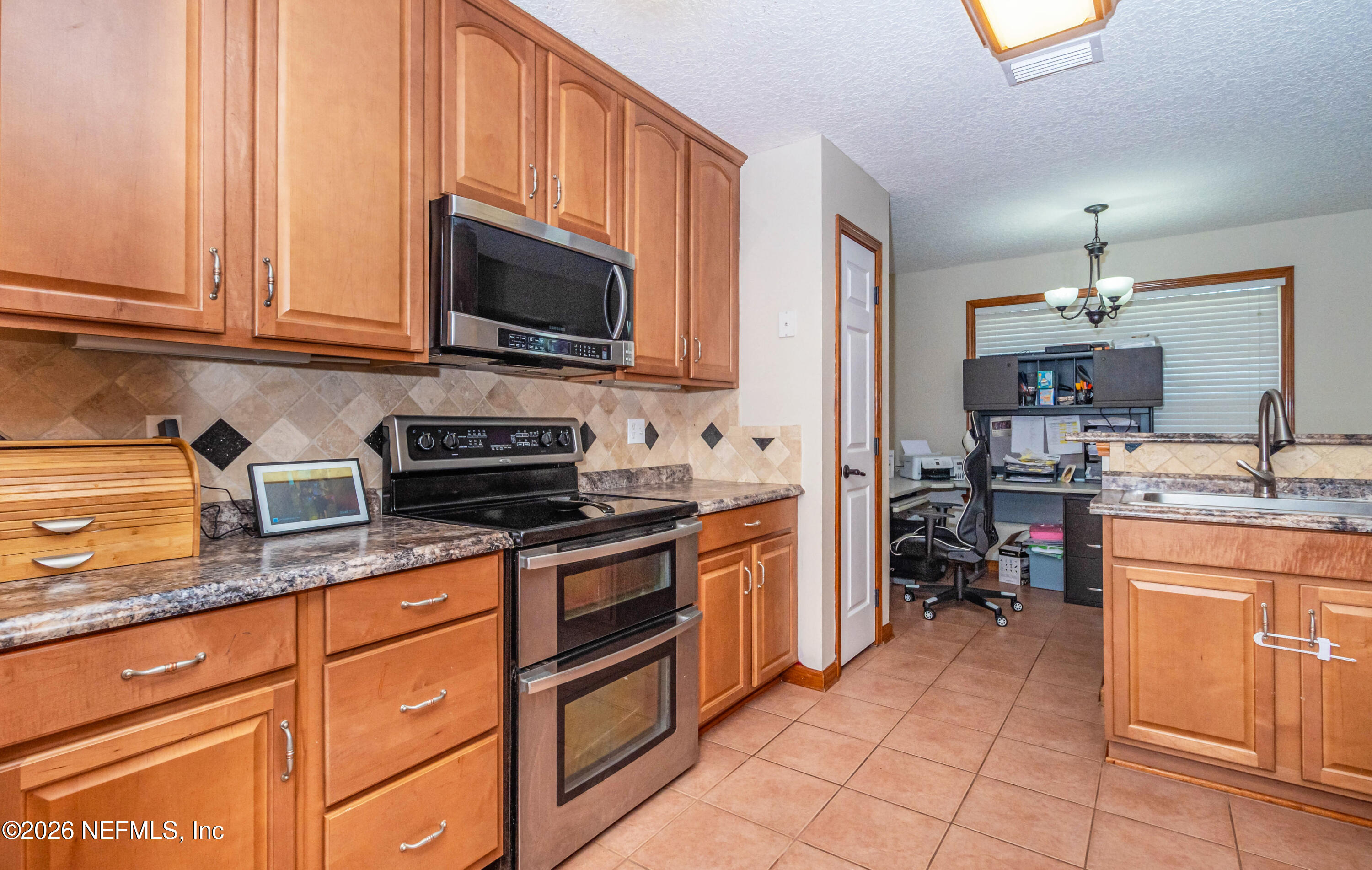 7667 Odis Yarborough Road Glen St. Mary, FL 32040 - Photo 17 of 40 a kitchen with stainless steel appliances granite countertop a stove a sink and a microwave