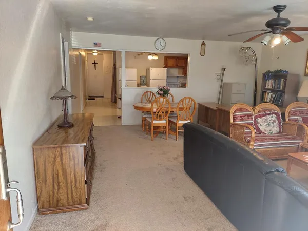 a living room with furniture a chandelier fan and a dining table