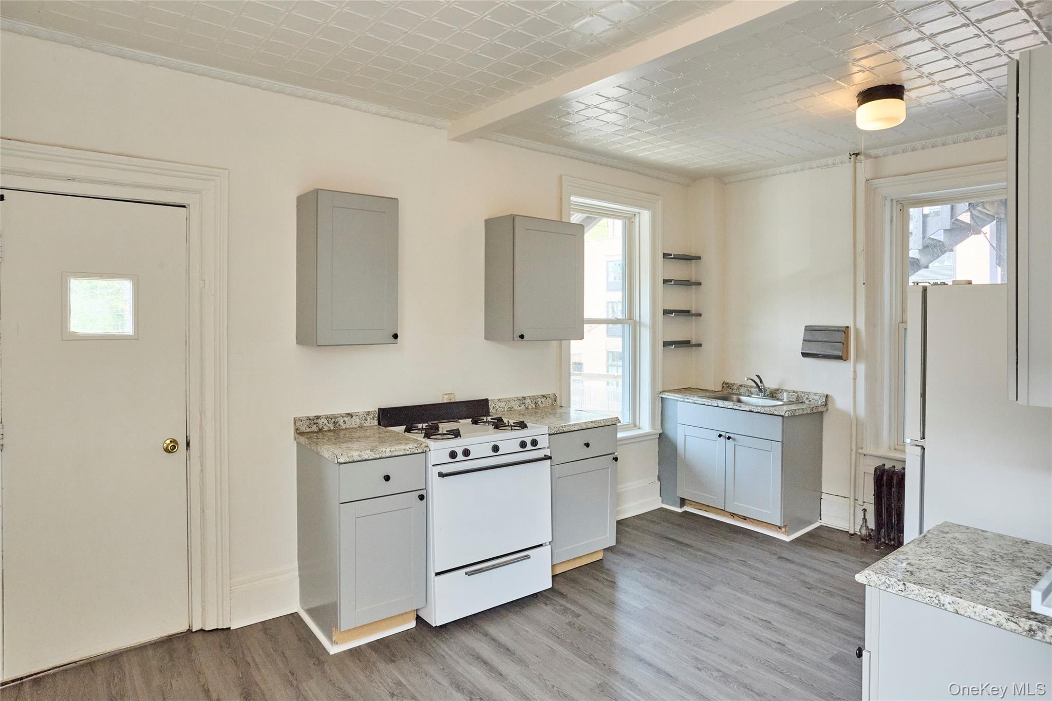 457 Main Street, Unit 3 Beacon, NY 12508 - Photo 3 of 13 a kitchen with stainless steel appliances white cabinets and wooden floor