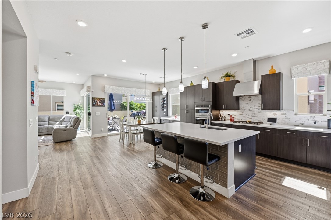 4246 Swift Street Las Vegas, NV 89135 - Photo 16 of 71 Kitchen featuring dark wood finish cabinets, a kitchen bar, an island with sink, pendant lighting, and modern cabinets