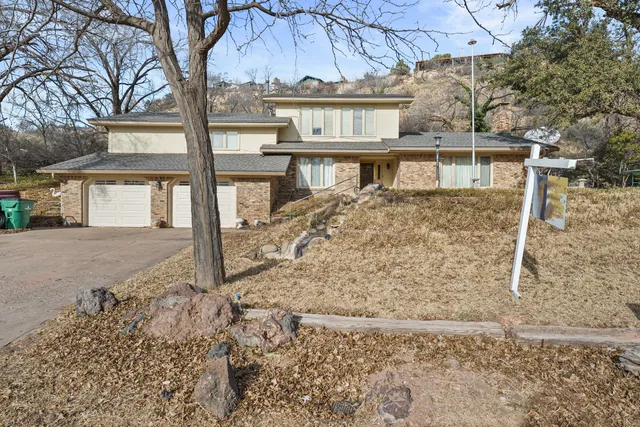 a view of a house with large trees next to a road
