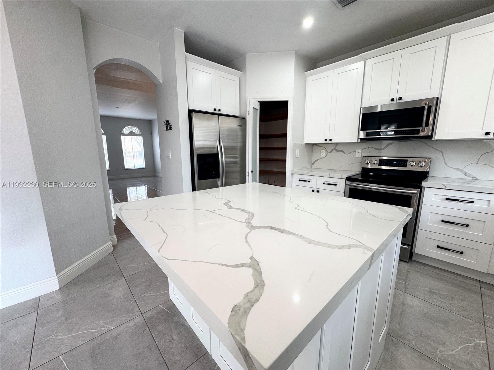 12283 Southwest 123rd Terrace Miami, FL 33186 - Photo 32 of 46 a kitchen with stainless steel appliances a refrigerator a stove a microwave and cabinets