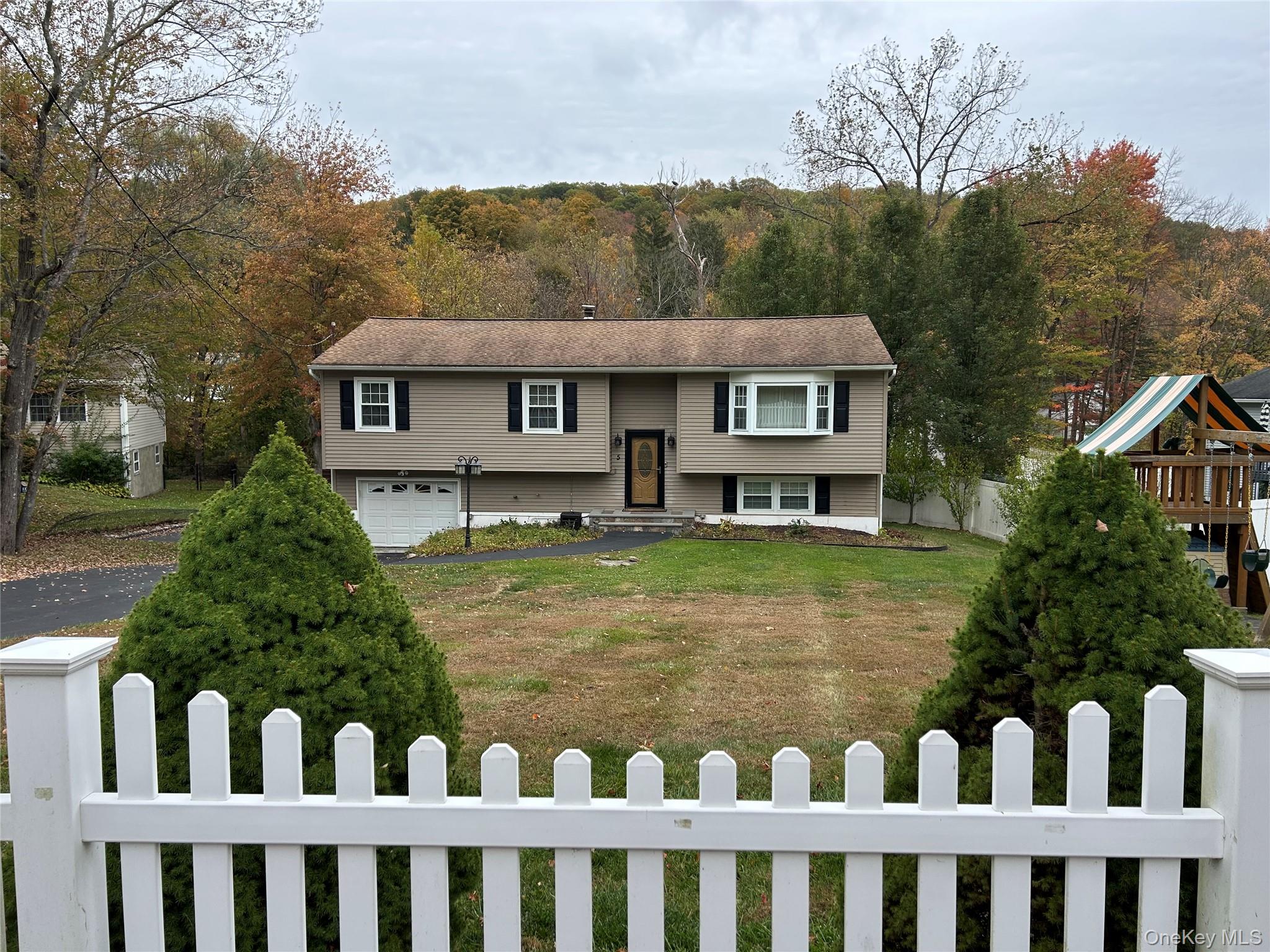 5 Kensico Road Carmel, NY 10512 - Photo 1 of 1 Raise Ranch home featuring a fenced front yard, a garage, driveway, and a playground