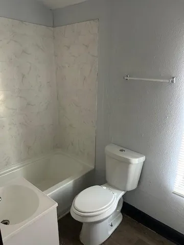 a white toilet sitting next to a bath tub
