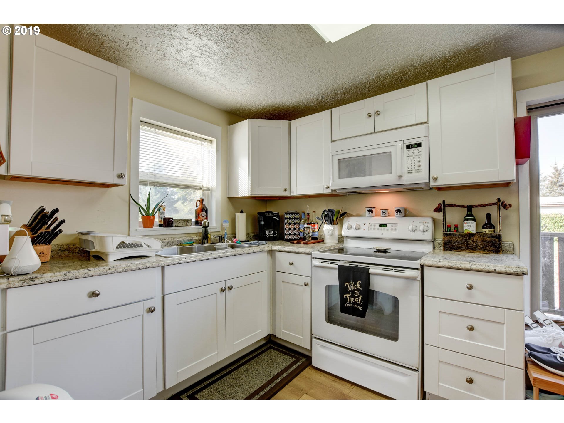 92411 Carnegie Road Astoria, OR 97103 - Photo 11 of 23 a kitchen with granite countertop white cabinets and white appliances