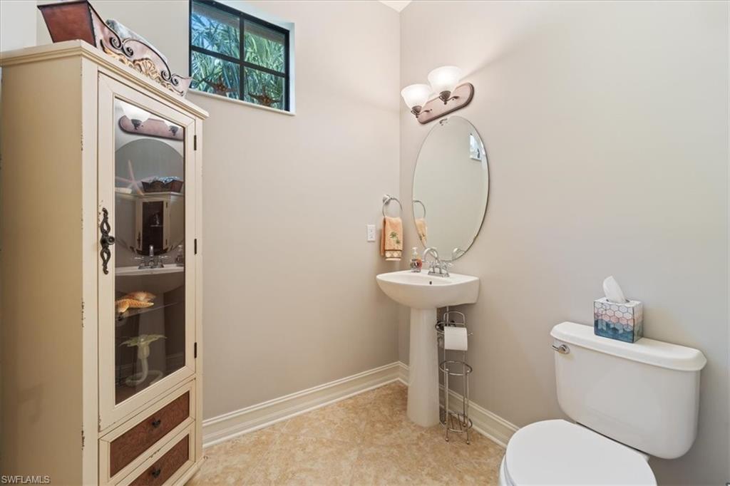 9091 Covina Drive South, Unit 6904 Naples, FL 34113 - Photo 22 of 46 a bathroom with a toilet a sink and mirror