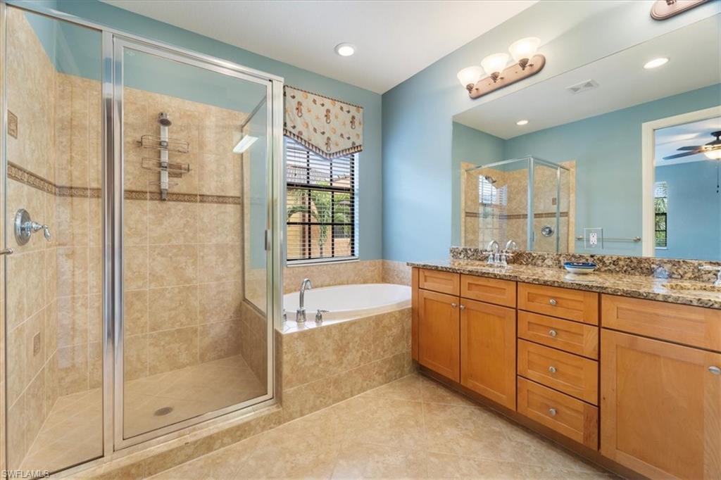 9091 Covina Drive South, Unit 6904 Naples, FL 34113 - Photo 27 of 46 a spacious bathroom with a granite countertop sink a mirror a shower and a bathtub