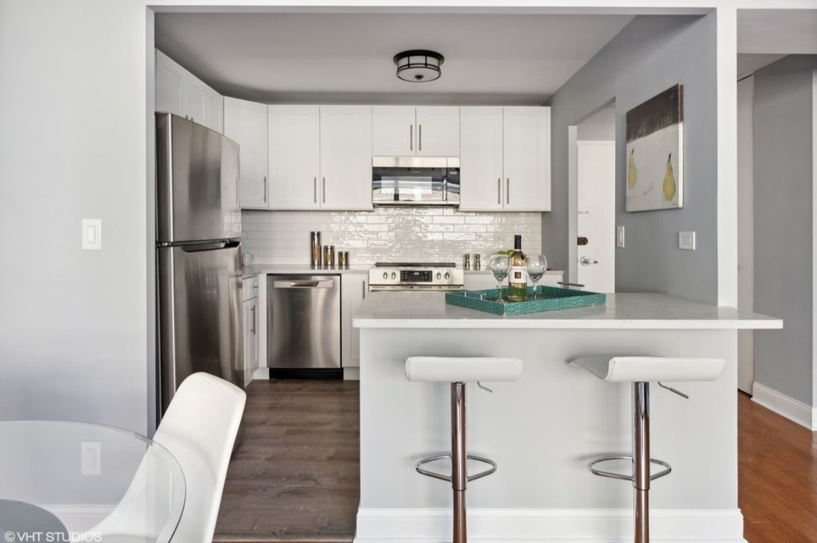 6301 North Sheridan Road, Unit 19D Chicago, IL 60660 - Photo 6 of 11 a kitchen with stainless steel appliances granite countertop a refrigerator a stove a sink dishwasher and white cabinets with wooden floor