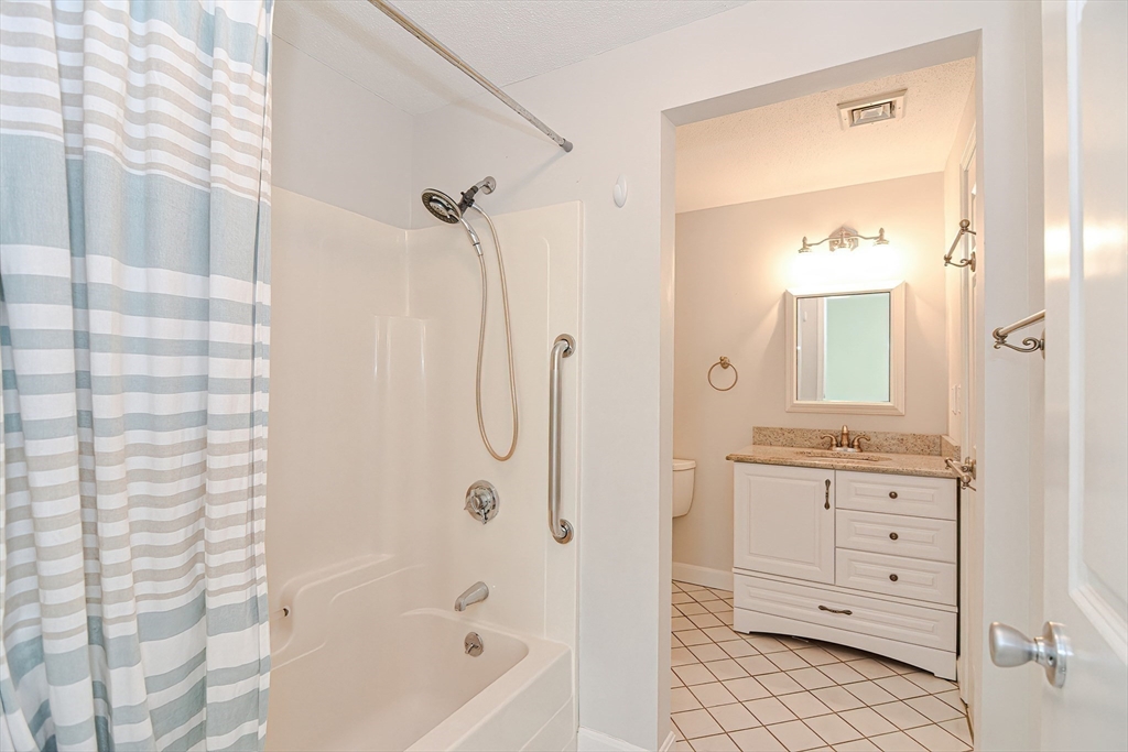 2743 Cranberry Highway, Unit 2D Wareham, MA 02571 - Photo 26 of 37 a bathroom with a granite countertop sink a mirror a vanity and a bathtub
