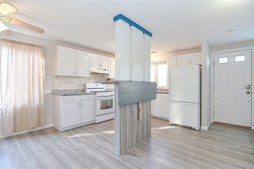 2743 Cranberry Highway, Unit 2D Wareham, MA 02571 - Photo 7 of 37 a kitchen with a refrigerator a stove top oven and white wooden cabinets