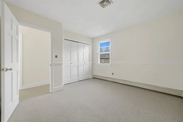 an empty room with chandelier fan and windows