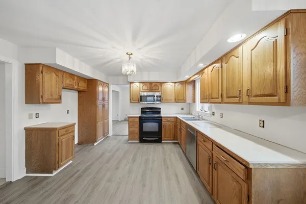 a large kitchen with a large counter top space a sink stainless steel appliances and cabinets