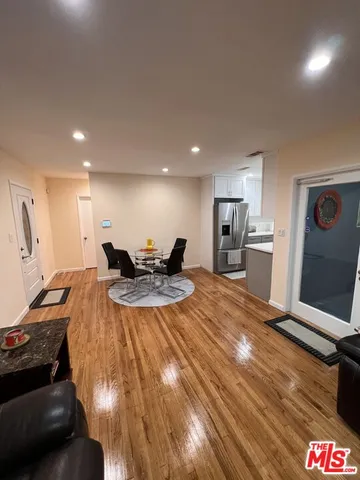 a living room with stainless steel appliances furniture a rug and a large window