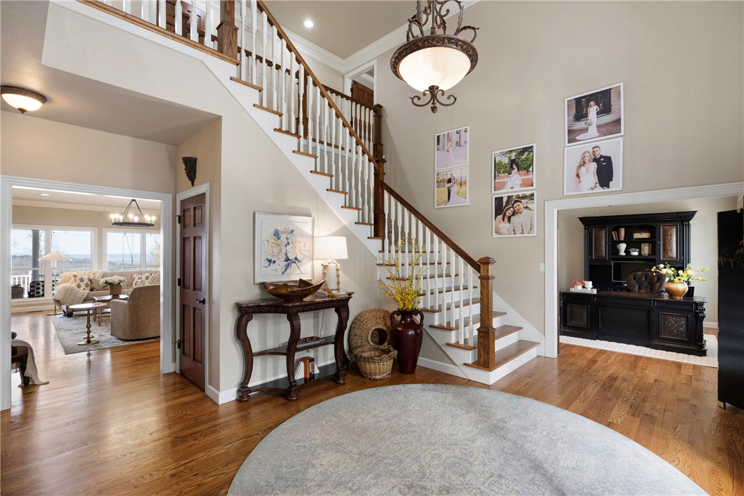 Foyer with hanging lights, wood finished floors, crown molding, and a high ceiling
