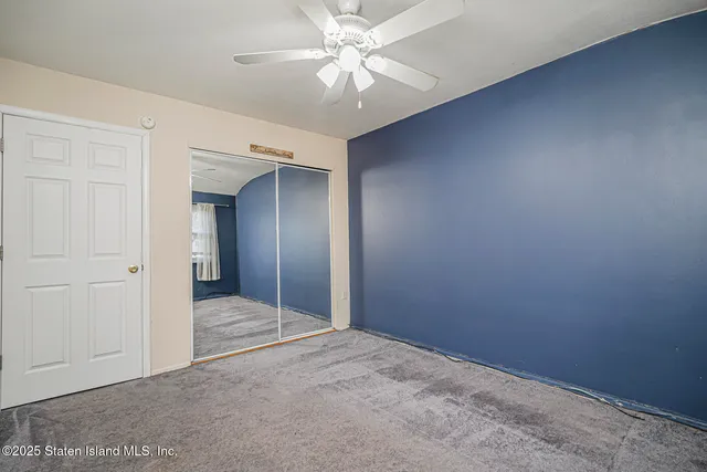 an empty room with closet and a ceiling fan