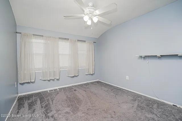 an empty room with chandelier fan and windows