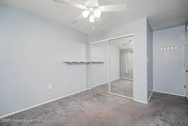 an empty room with closet and a chandelier fan