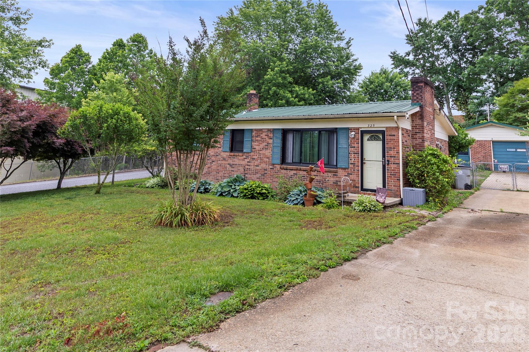 325 Swanson Road Lenoir, NC 28645 - Photo 2 of 35 a view of a yard in front of a house with plants and large tree