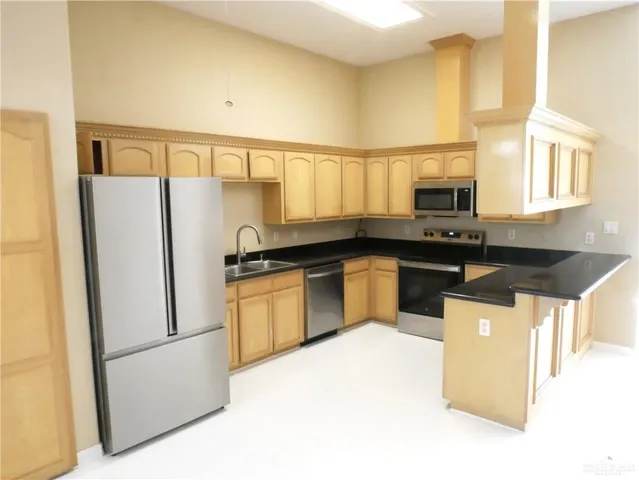 a kitchen with stainless steel appliances granite countertop a refrigerator a sink a stove a microwave a counter space and cabinets