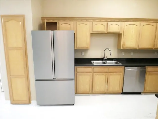 a kitchen with stainless steel appliances a refrigerator a sink and cabinets