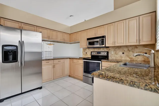 a kitchen with granite countertop a refrigerator sink and microwave