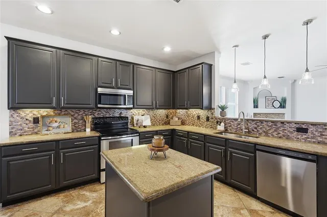 a kitchen with kitchen island granite countertop a sink stove and refrigerator