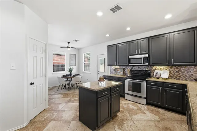 a kitchen with stainless steel appliances granite countertop a stove top oven a sink dishwasher a dining table and chairs