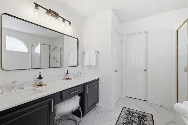 a spacious bathroom with a double vanity sink a mirror and shower