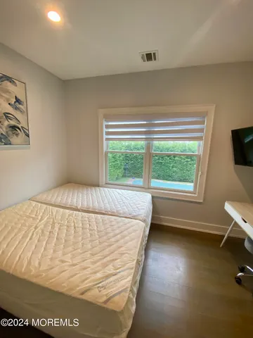 a view of a bedroom with wooden floor and a window