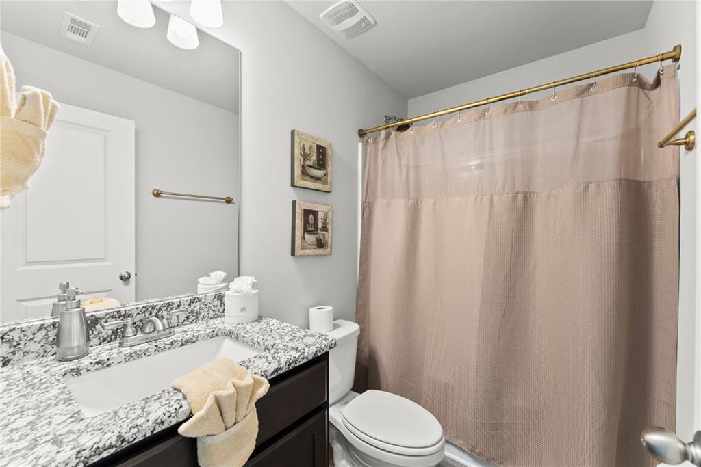 527 Gadwall Circle Jefferson, GA 30549 - Photo 32 of 48 a bathroom with a granite countertop sink toilet a mirror and shower curtain