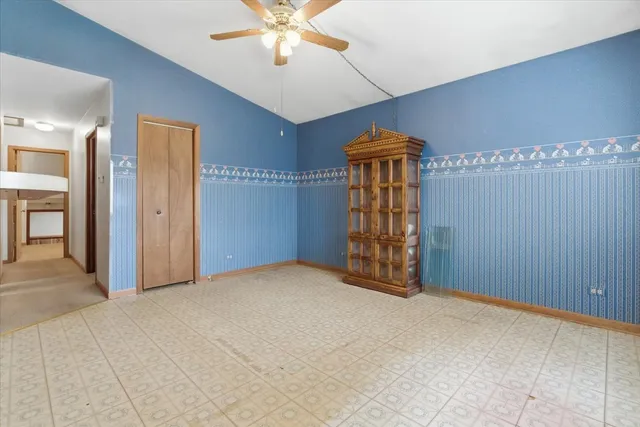 a view of an empty room with window and chandelier fan