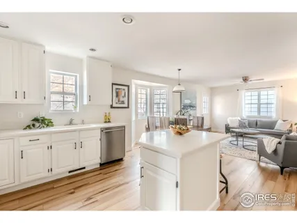 a large white kitchen with cabinets a sink a window and stainless steel appliances