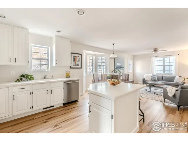 a large white kitchen with cabinets a sink a window and stainless steel appliances