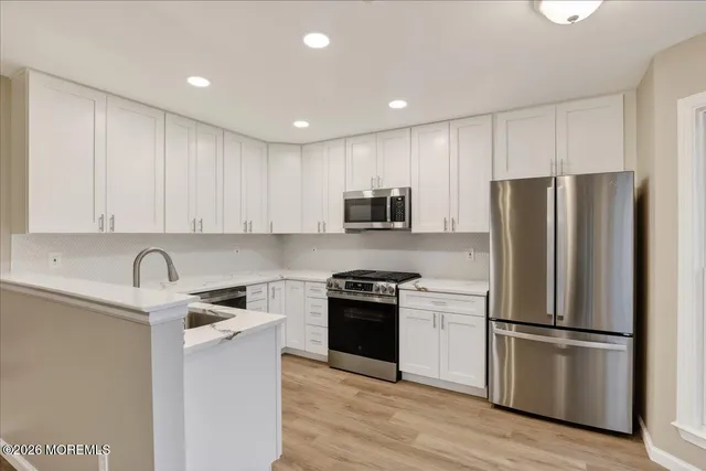 a kitchen with a refrigerator sink and white cabinets