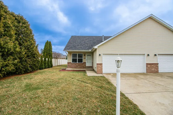 a front view of house with yard and trees in the background