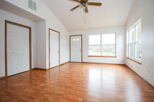 a view of an empty room with a window and wooden floor