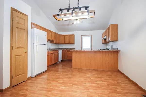 a kitchen with stainless steel appliances granite countertop a sink dishwasher a refrigerator and a stove with wooden floor